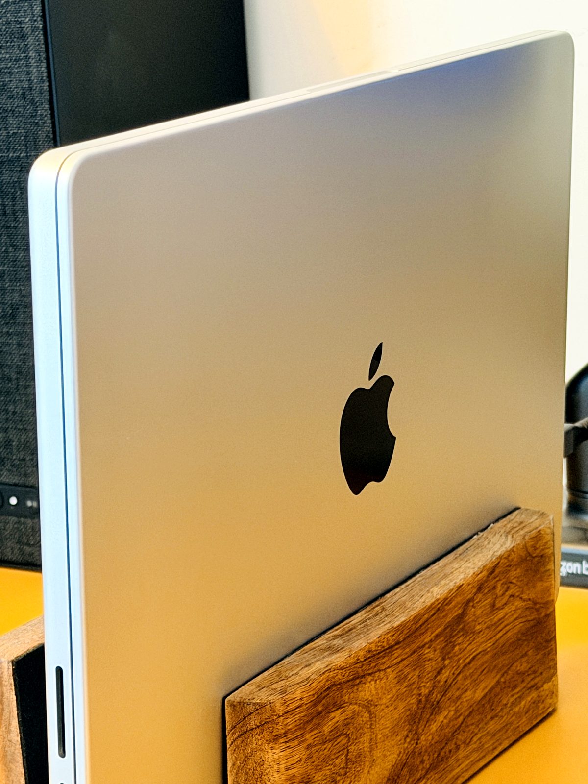 MacBook Pro M5 Pro resting on a vertical wooden side stand